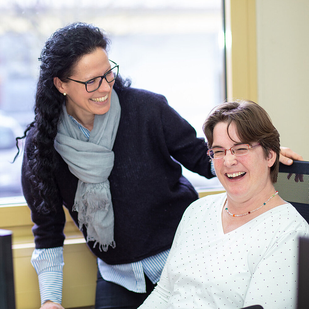 Zwei Frauen lachen in einem Büro